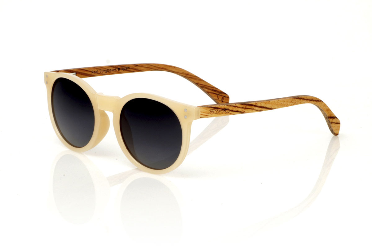 Wood eyewear of Zebrano INKY. INKY sunglasses capture the essence of a delicate and feminine design with their rounded shape and smaller size. The frame in a sophisticated satin-gloss ivory offers a touch of light and elegance, while the zebrawood temples introduce a natural and striking contrast. This model is ideal for those looking for distinctive but subtle glasses that complement without overloading. With measurements of 138x48mm and a caliber of 47, the INKY adapts perfectly to thinner faces, ensuring comfort and style. Immerse yourself in the beauty of the details to enhance your look with a unique charm. for Wholesale & Retail | Root Sunglasses® 